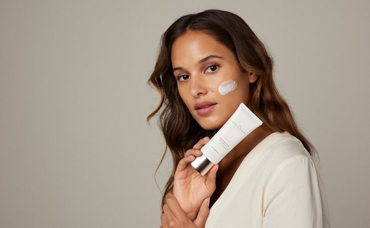 A woman applies Rituals skin brightening exfoliator for glowing skin. 