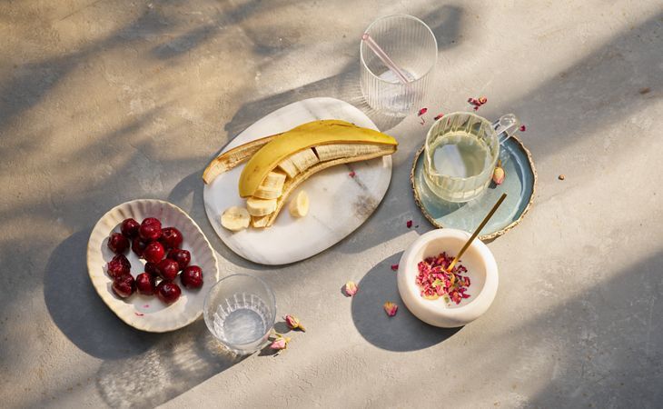 Ingrédients frais entrant dans la préparation de notre recette de smoothie bonne mine : bananes, cerises, pétales de rose et jus de citron.