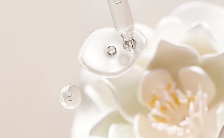 A dropper with hyaluronic acid serum and holy lotus extract, highlighting hydrating skincare ingredients.