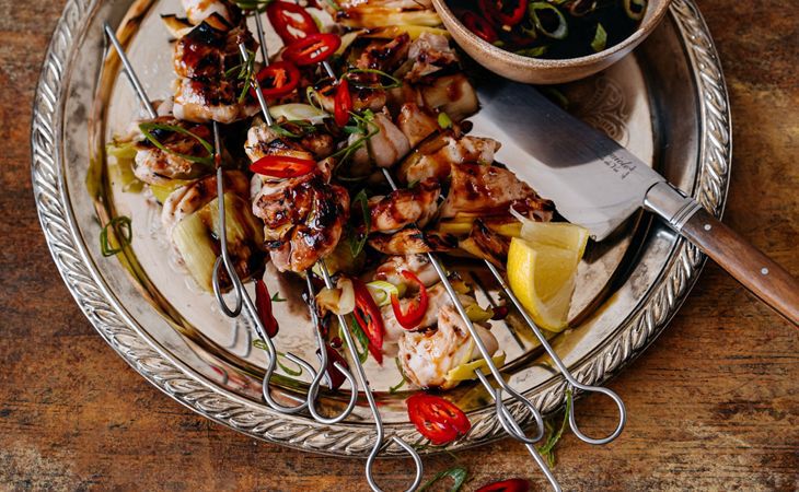 Grillowane szaszłyki z kurczaka z czerwoną papryczką chili, kawałkami cytryny i sosem jako pożywna kolacja.