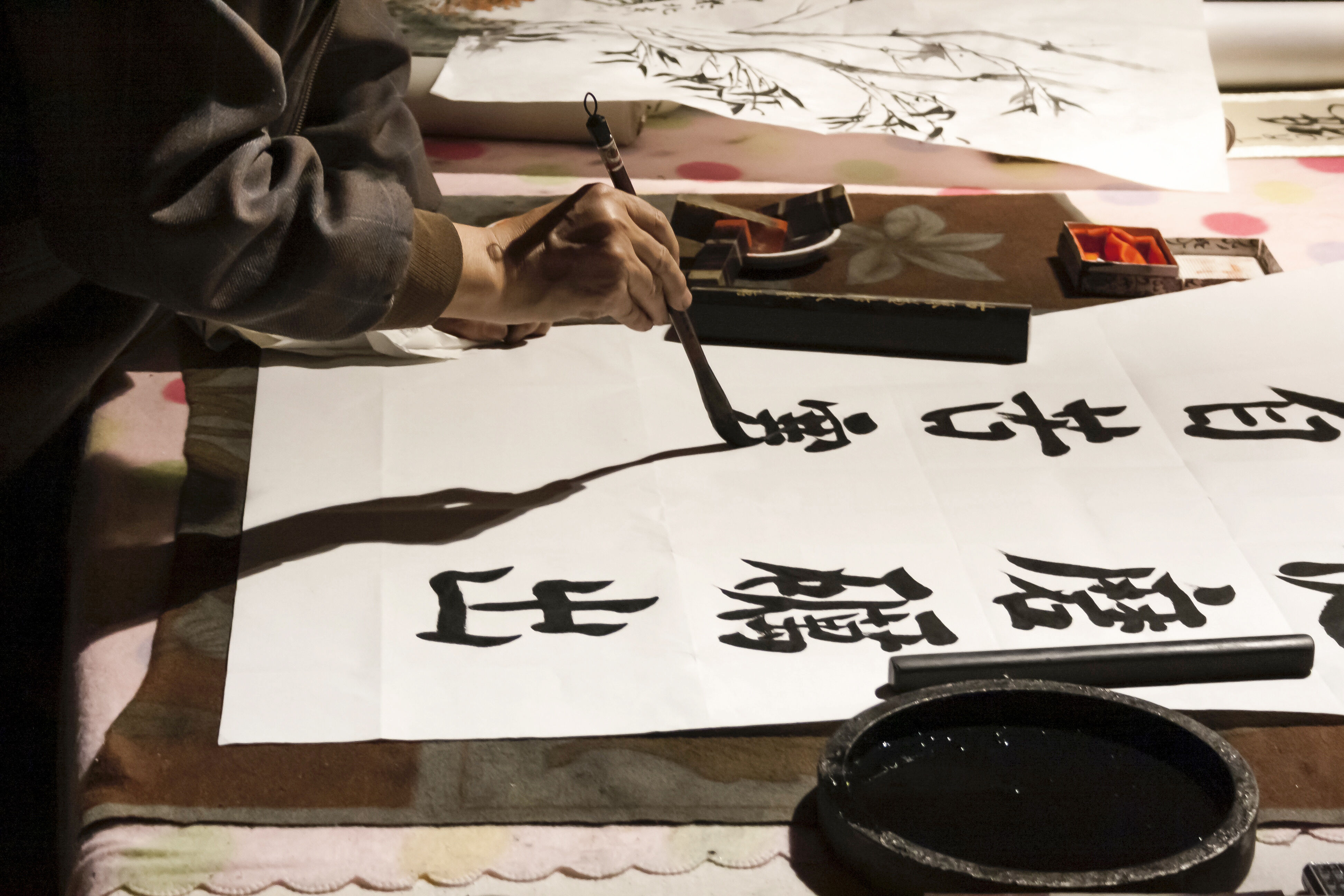 Eine Person, die mit einem Pinsel japanische Kalligrafiezeichen malt und sich durch diese traditionelle Kunst in Achtsamkeit übt.