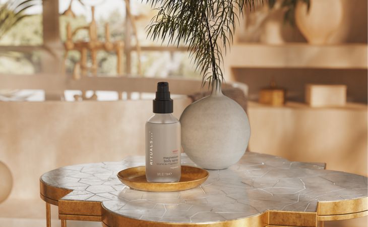 A bottle of Rituals Sport collection magnesium spray for sore muscles, shown on a luxurious marble bathoom counter top. 